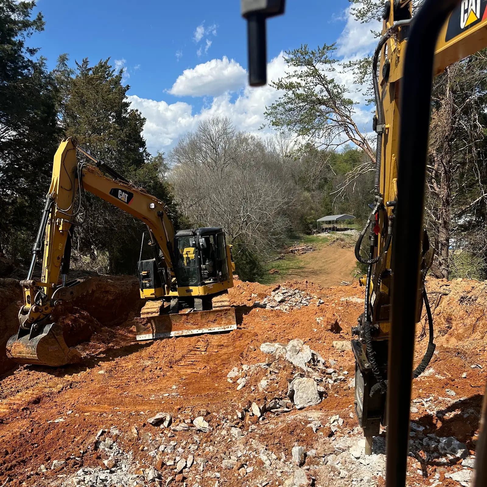 Excavators clearing and breaking ground on a wooded site