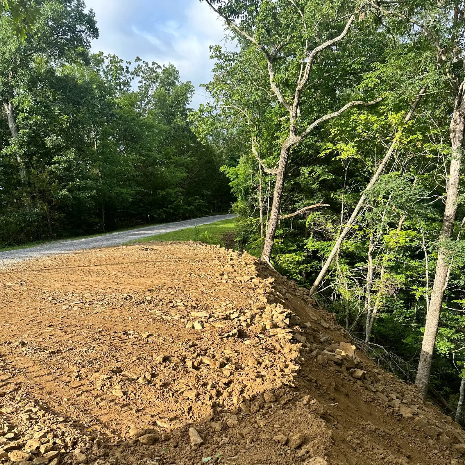 Freshly graded earthwork along a wooded property